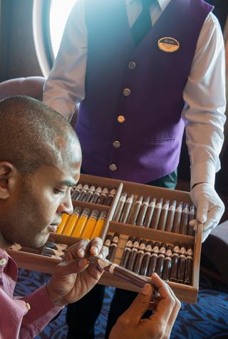 A waiter presents a selection of cigars to a guest enjoying a drink at the bar | MSC Cruises