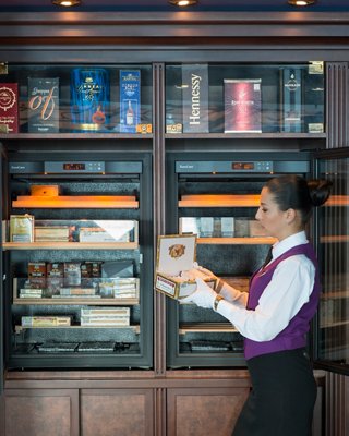 A waiter carefully handles a cigar box in the ship's bar, showcasing attentive service on board | MSC Cruises