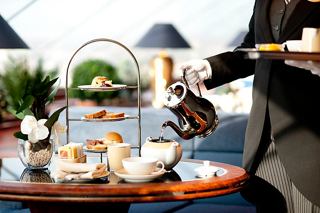 A butler serves an elegant breakfast tray with pastries and beverages in the luxurious MSC Yacht Club | MSC Cruises