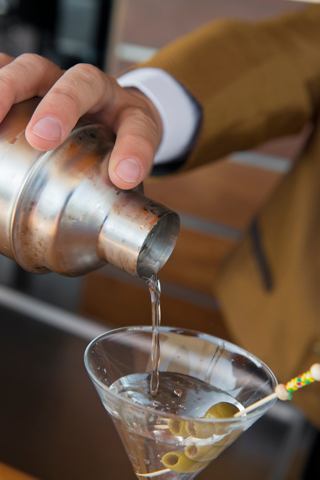 A bartender skillfully prepares a cocktail, pouring it into a glass with garnishes | MSC Cruises