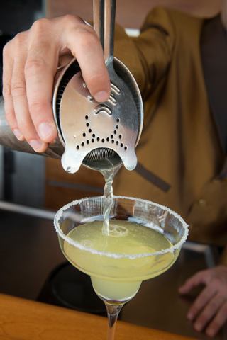 A bartender skillfully pours a fresh cocktail through a strainer into a glass, ready to be served | MSC Cruises