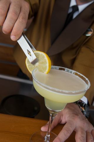 A bartender garnishes a cocktail with a slice of lemon, showcasing the art of mixology on MSC Splendida | MSC Cruises