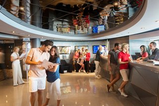 Guests interact with the staff at the excursion office on MSC Divina | MSC Cruises