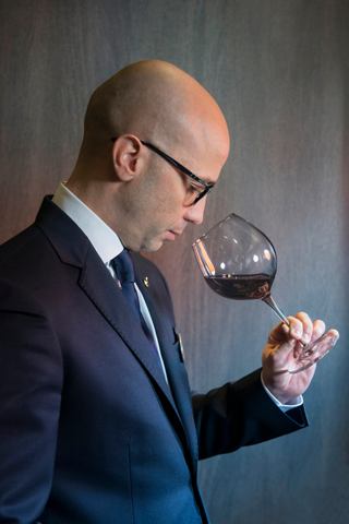 A sommelier in a suit tasting wine from a glass, showcasing expertise and passion for fine beverages | MSC Cruises
