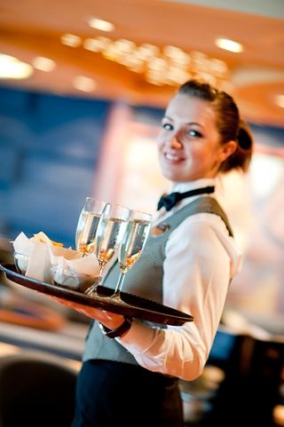 A friendly waiter serves drinks on a tray, embodying exceptional hospitality aboard MSC Splendida | MSC Cruises