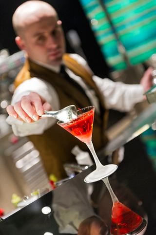 A skilled bartender presents a vibrant cocktail at The Green Sax Jazz Bar on MSC Preziosa | MSC Cruises