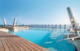 Une zone de piscine sereine sur le MSC Divina avec des chaises longues et un ciel bleu clair invitant à la détente | MSC Croisières