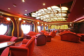 Un bar acogedor con sofás rojos y una iluminación elegante, perfecto para relajarse y socializar | MSC Cruceros