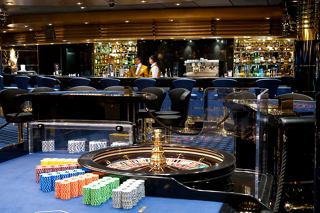 A vibrant casino scene on MSC Magnifica featuring a roulette wheel and a stylish bar area | MSC Cruises
