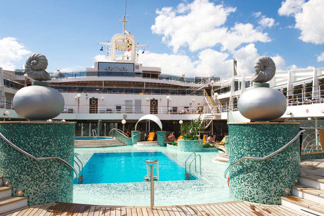 The inviting pool area of MSC Magnifica surrounded by elegant sculptures and bright skies | MSC Cruises
