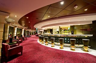 A stylish bar area featuring a curved counter, plush seating, and warm lighting aboard MSC Magnifica | MSC Cruises