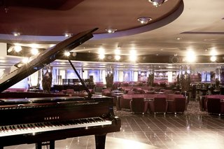 The elegant L'Ametista Lounge features plush seating and a piano, inviting guests to relax and enjoy the atmosphere | MSC Cruises