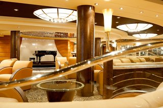 A warm and inviting lounge area featuring elegant armchairs and a piano, perfect for relaxation and socialising | MSC Cruises