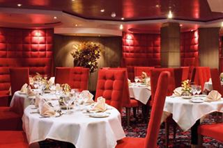 Elegant dining area with red walls and beautifully set tables | MSC Cruises