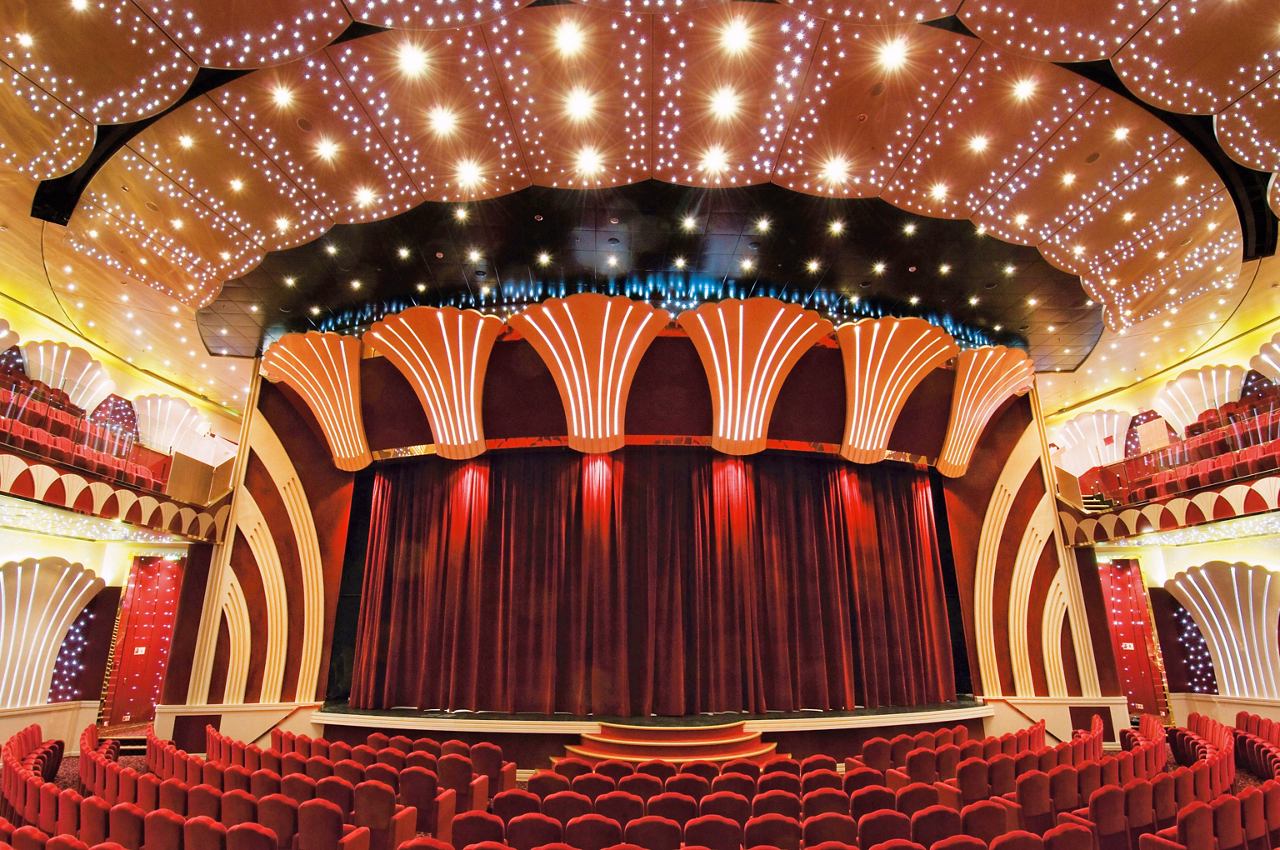 A spacious theatre with a grand stage, red curtains, and elegant seating, ready for spectacular performances | MSC Cruises