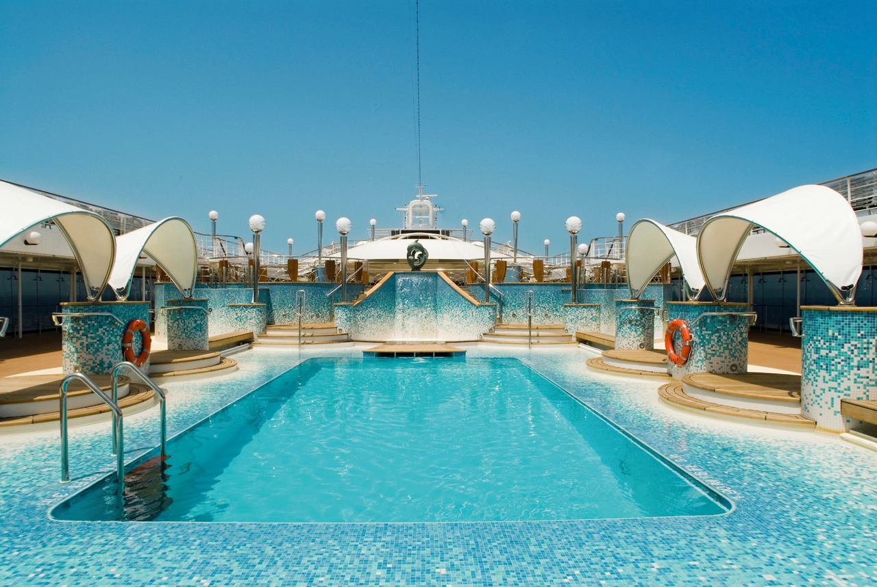 A serene swimming pool surrounded by sun loungers and a clear blue sky on the MSC Musica deck | MSC Cruises