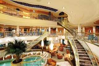 The elegant reception area features a sweeping staircase and inviting decor for guests arriving at MSC Poesia | MSC Cruises