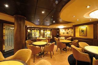 Une salle de cartes chaleureuse et accueillante avec des tables et des fauteuils conçus pour la détente et le divertissement | MSC Croisières