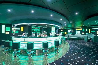 A stylish bar area with green lighting, inviting seating, and a vibrant atmosphere for relaxation and enjoyment | MSC Cruises