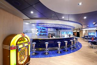 A vibrant bar area on MSC Preziosa featuring a jukebox, seating, and a welcoming atmosphere for relaxation | MSC Cruises