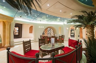 A welcoming lounge area featuring plush seating and a central table, surrounded by decorative palm details | MSC Cruises