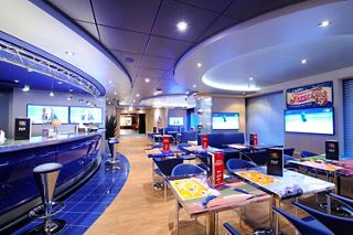 A vibrant sports bar and dining area on MSC Preziosa featuring tables, chairs, and screens for entertainment | MSC Cruises