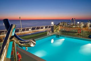 A serene poolside view at sunset, overlooking the sea and sky, with vibrant colours reflecting the tranquil atmosphere | MSC Cruises