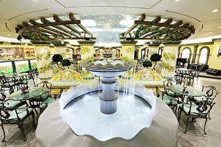 A beautifully arranged bar area with tables and a fountain, featuring warm décor for a welcoming atmosphere | MSC Cruises