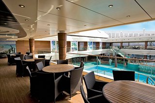 Inviting dining area by the pool featuring tables and chairs surrounded by palm trees on MSC Splendida | MSC Cruises