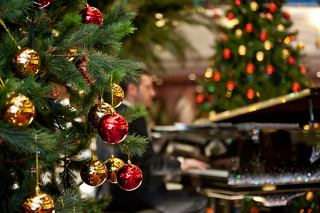 A musician plays the piano beside festive Christmas decorations in the reception area of MSC Splendida | MSC Cruises