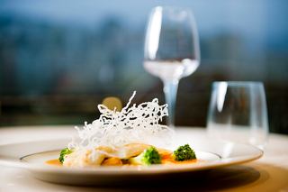 Un plat principal magnifiquement présenté avec du poisson et des brocolis sur une assiette avec une verrerie élégante | MSC Croisières
