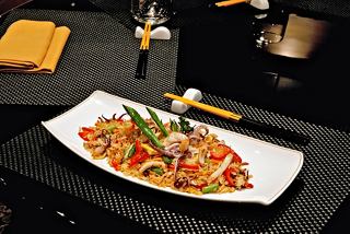 Un plato bellamente presentado con arroz, pescado y verduras, servido en una mesa con palillos | MSC Cruceros