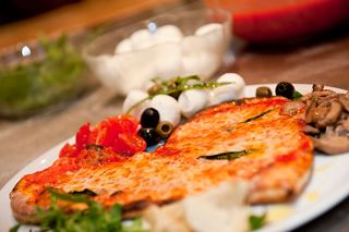 A vibrant plate featuring a delicious pizza topped with mozzarella, tomato, mushrooms, and olives | MSC Cruises