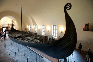 A Viking ship on display at the Viking Ship Museum in Oslo, Norway, surrounded by warm lighting | MSC Cruises
