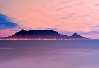 Ein atemberaubender Blick auf den Sonnenuntergang über dem Tafelberg in Kapstadt, Südafrika, der sich im ruhigen Meer spiegelt | MSC Cruises