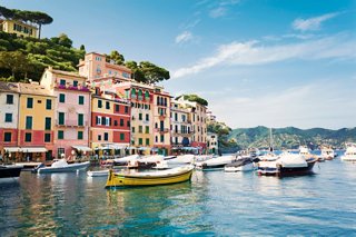 A picturesque view of Portofino's colourful houses lining the tranquil sea with boats gently floating | MSC Cruises
