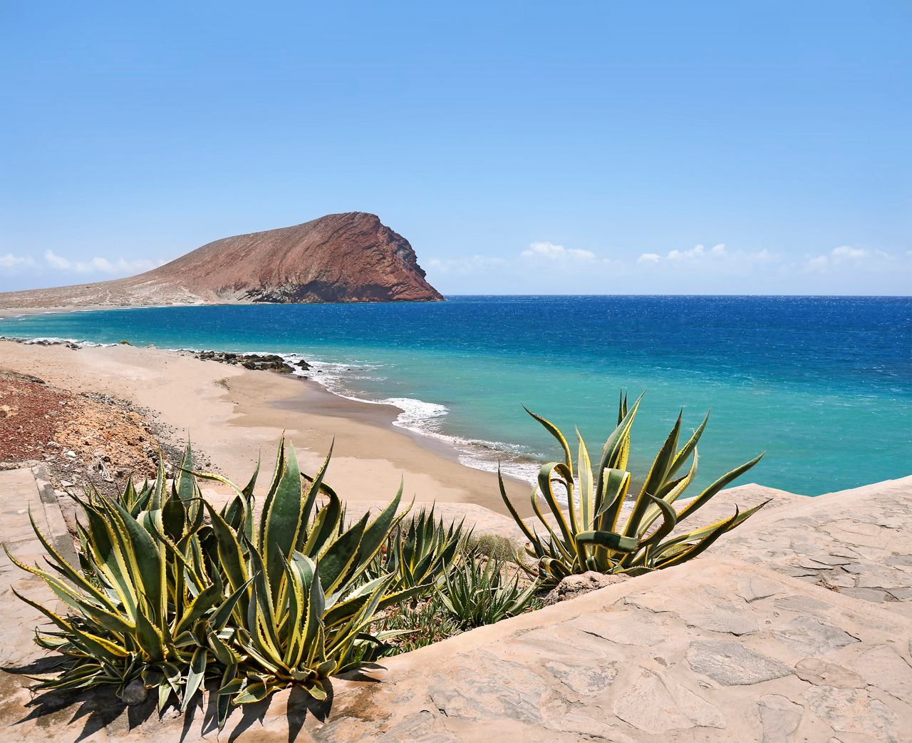 Une vue époustouflante d'une plage de sable avec une mer vibrante et un promontoire rocheux à Ténérife, invitant à l'exploration et à la détente | MSC Cruises
