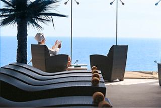 Eine Frau entspannt in einem Stuhl neben einem Fenster mit Blick auf das Meer im MSC Aurea Spa | MSC Cruises