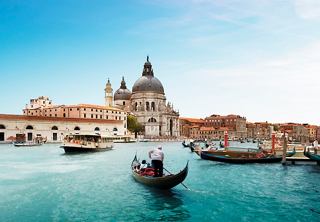 Ein ruhiger Kanal in Venedig mit Gondeln und einer schönen Kirche im Hintergrund, die zur Erkundung und zum Staunen einlädt | MSC Cruises