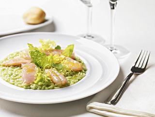 A beautifully presented plate of risotto garnished with fresh ingredients and accompanied by a fork | MSC Cruises