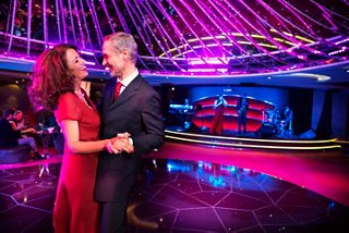 Una pareja baila junta en el Aft Lounge, rodeada de luces vibrantes y un ambiente animado | MSC Cruceros