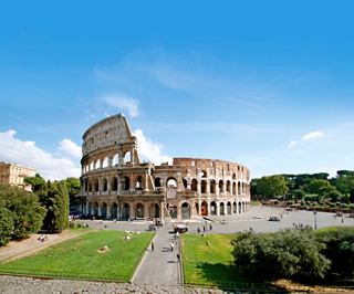 Das ikonische Kolosseum in Rom, umgeben von Grün unter einem klaren blauen Himmel | MSC Cruises