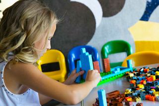 Ein Kind beteiligt sich fröhlich an einer spielerischen Aktivität im Kinderbereich mit bunten Bauklötzen | MSC Cruises
