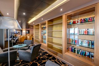 Cozy reading nook with comfortable armchairs and shelves filled with books | MSC Cruises