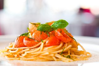 A delicious plate of pasta topped with fresh tomatoes and basil leaves | MSC Cruises