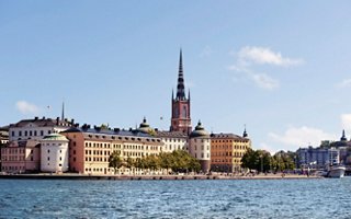 Une vue pittoresque du bord de l'eau de Stockholm avec des bâtiments historiques et un clocher sous un ciel bleu clair | MSC Croisières