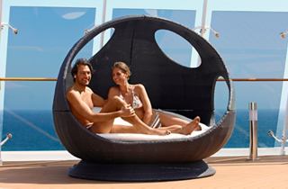 Ein Paar entspannt zusammen in einer kokonförmigen Lounge im Solarium und genießt die atemberaubende Aussicht auf das Meer | MSC Cruises