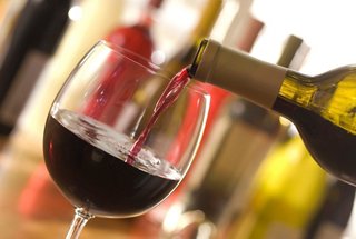 A glass of red wine being poured from a bottle, surrounded by various beverage bottles | MSC Cruises