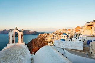 A picturesque Santorini village with white rooftops overlooking the serene sea at sunset | MSC Cruises