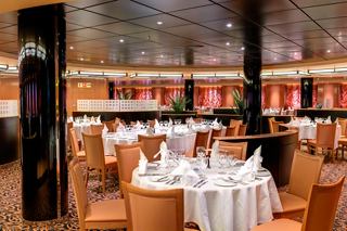 Un cadre de restaurant chaleureusement éclairé avec des tables et des chaises élégamment disposées, invitant les convives à vivre une expérience culinaire mémorable | MSC Croisières